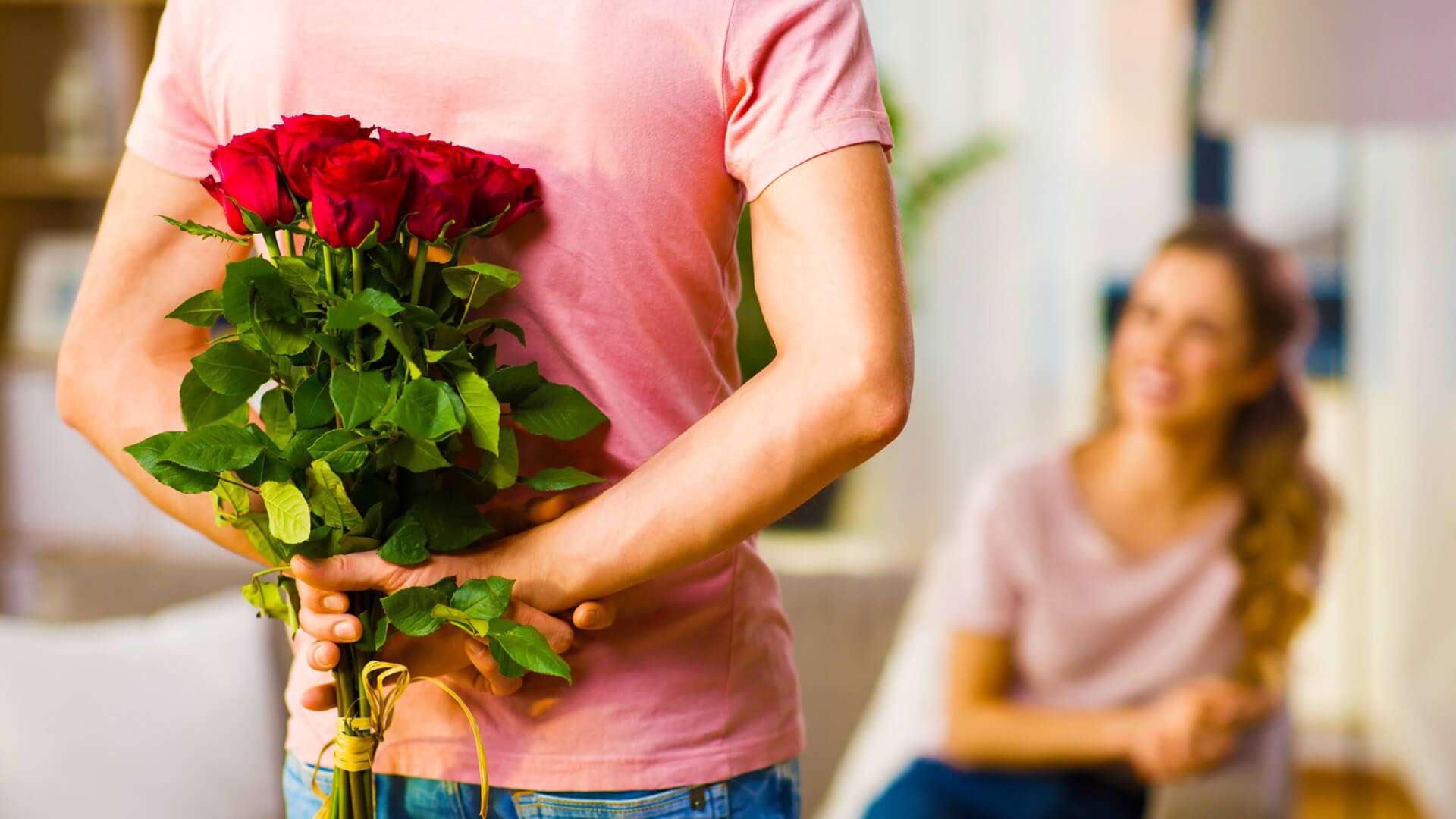 Мужчина с цветами. Букет роз за спиной. Парень дарит девушке цветы. Мужчина дарит цветы женщине.